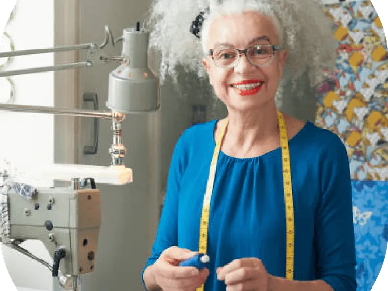 Une femme âgée travaille à la machine à coudre dans son atelier