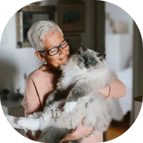 Une femme aux cheveux gris tient un chat à poils longs dans ses bras