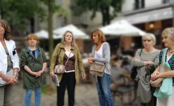 Un groupe de femmes discute dans une rue, devant la terrasse d'un café