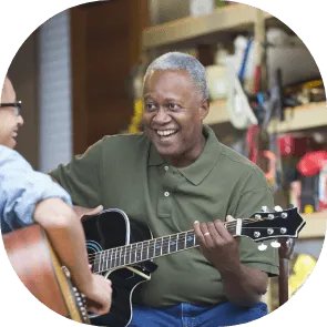 Jacques, souriant, joue de la guitare électrique dans un atelier