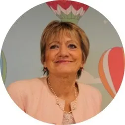 Portrait de Francyne, cheveux châtains courts et veste rose, devant un décor de montgolfière