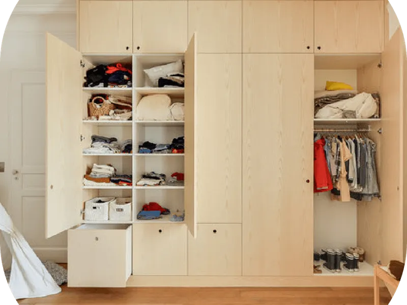 Un dressing en bois clair bien rangé, avec chaussures, boîtes et vêtements pliés